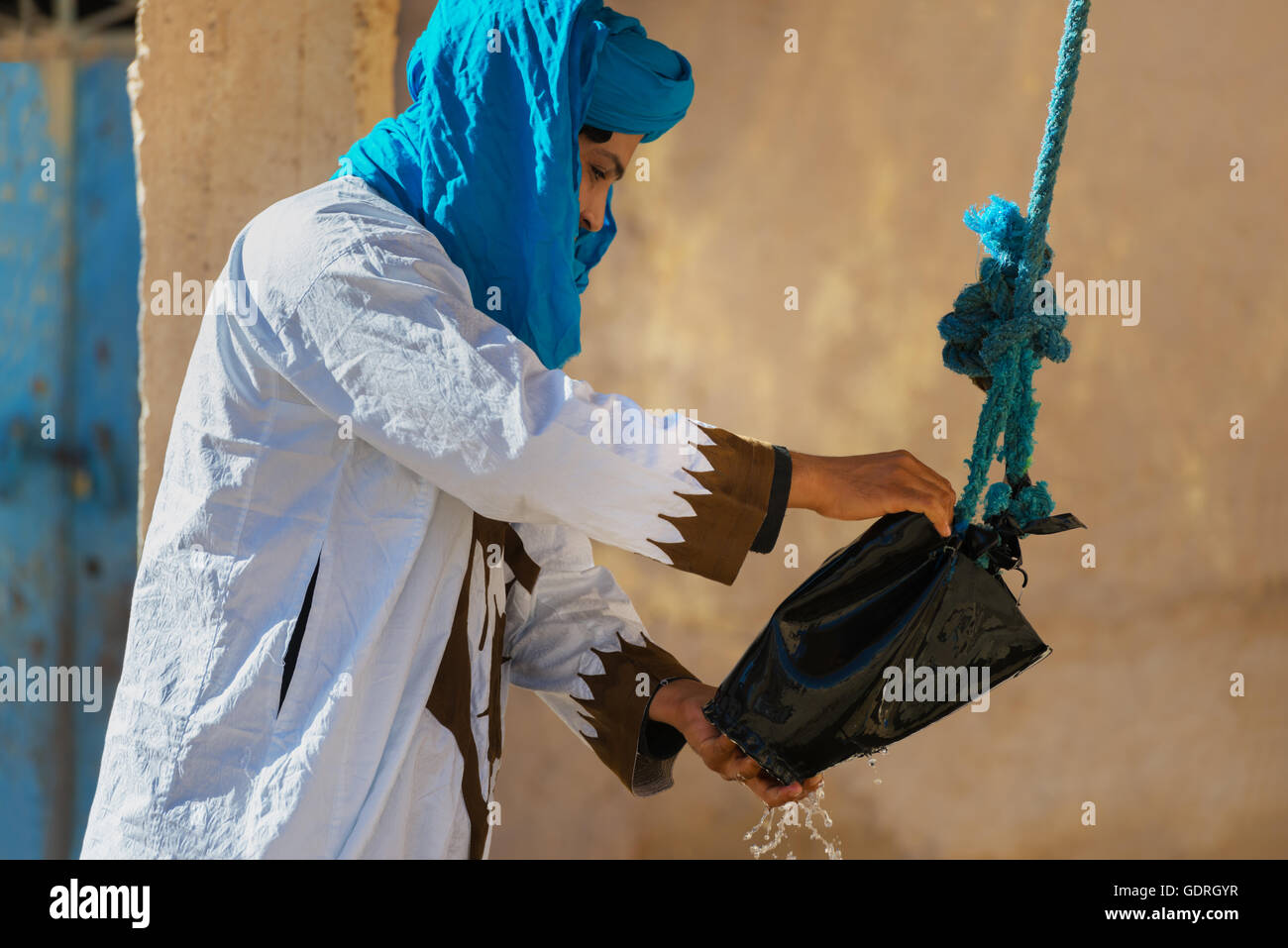 Habillés traditionnels homme obtient l'eau d'un puits. Banque D'Images