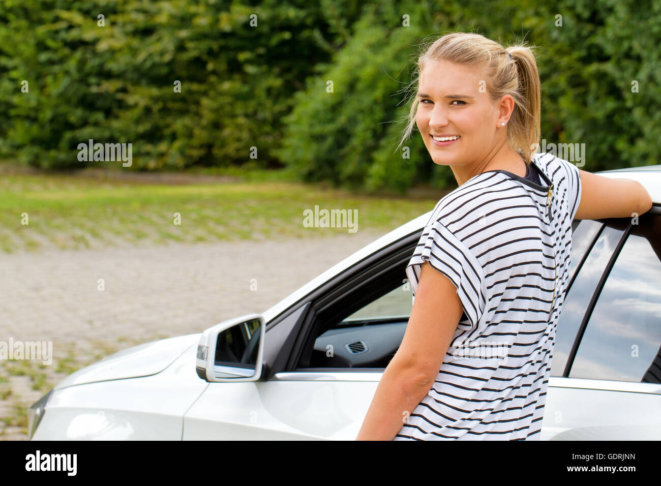 Jeune femme debout par sa nouvelle voiture Banque D'Images