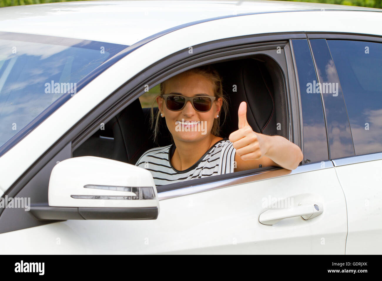 Happy girl with sunglasses dans une voiture avec thumb up Banque D'Images