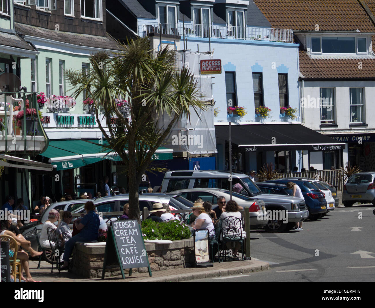 Les touristes s'asseoir et prendre un thé à la crème dans un café le long de Gorey Pier,Jersey, Channel Islands, Banque D'Images