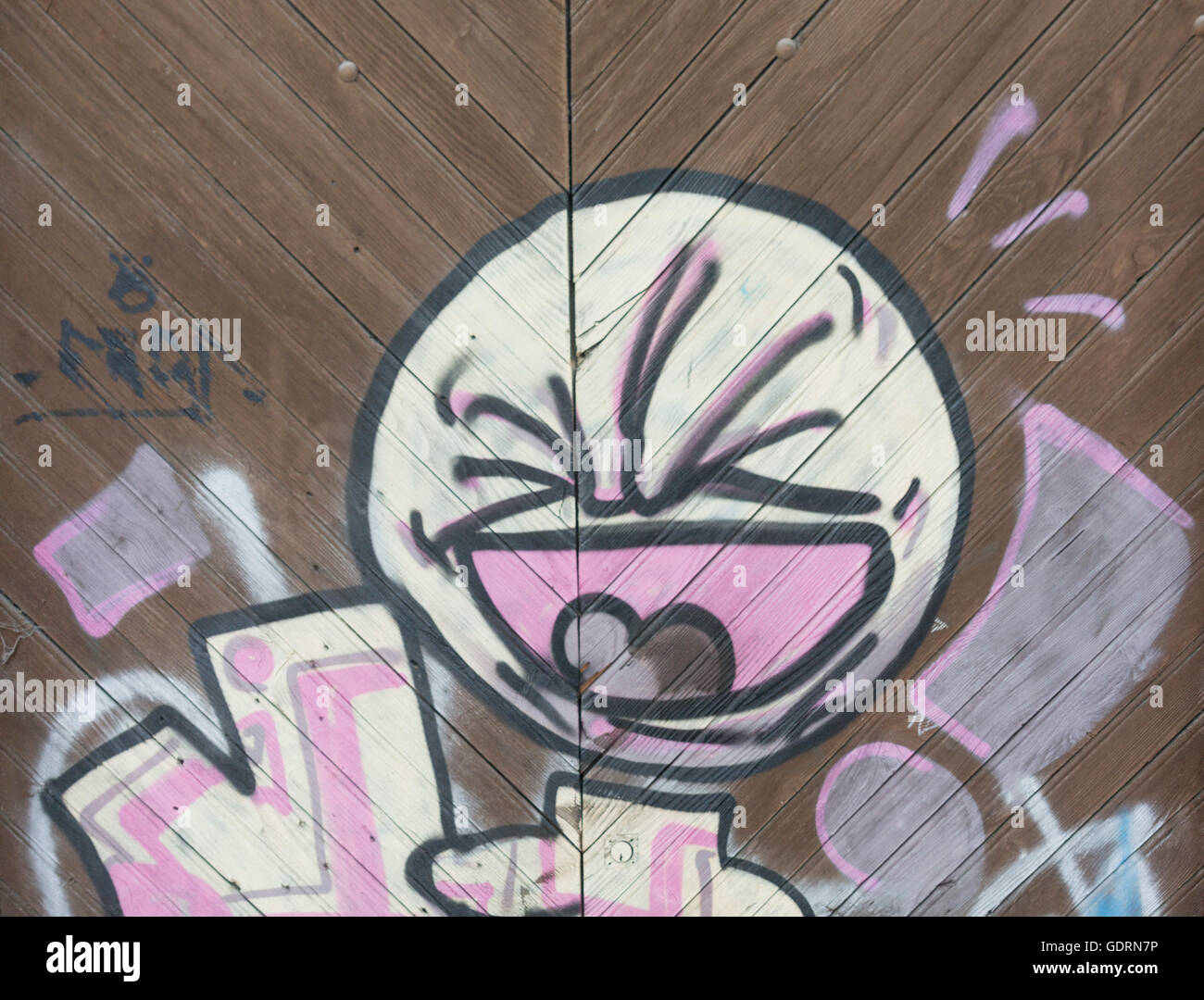 Un puissant art graffiti simple, connu sous le nom de 'Bambin', qui est pulvérisé sur une paroi revêtue, et une grande porte en bois. Banque D'Images