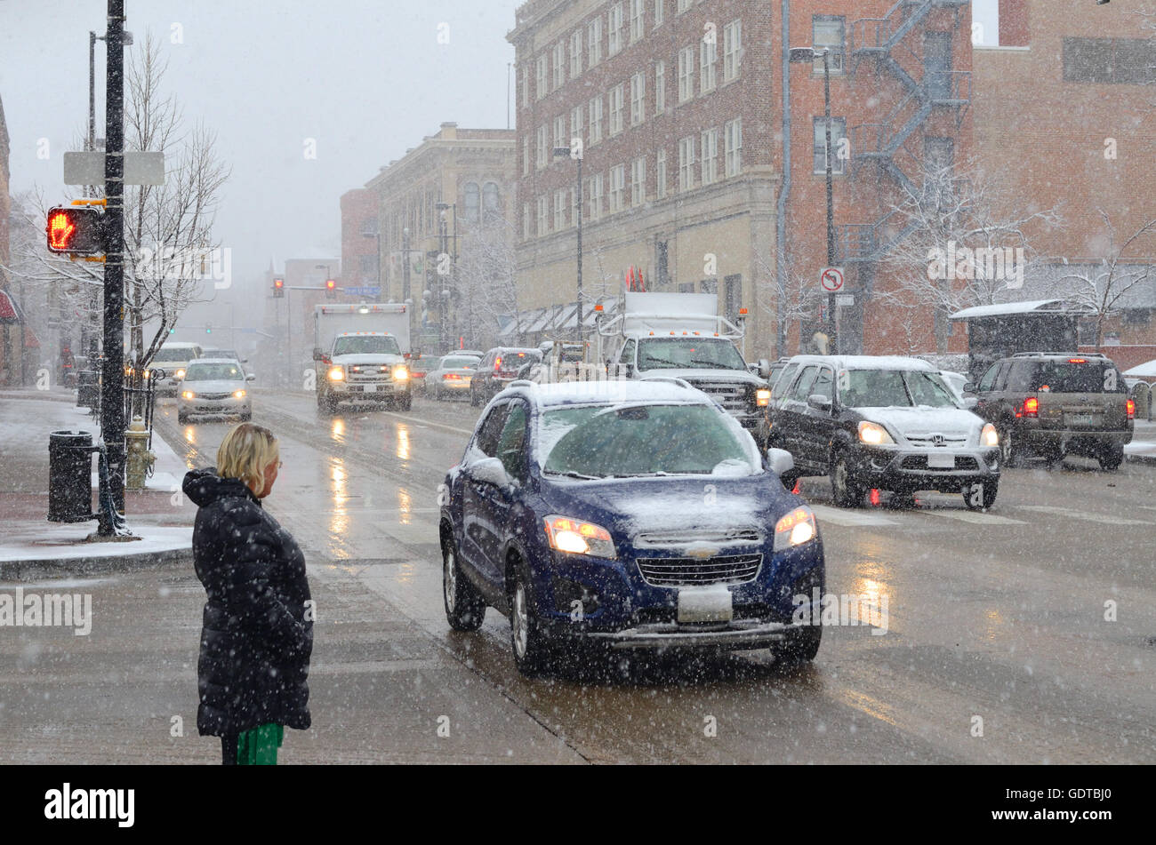 Attend de traverser les piétons rue Broadway, dans le centre-ville de Boulder, CO, lors d'une neige de printemps. Le grésil et la neige mouillée Banque D'Images