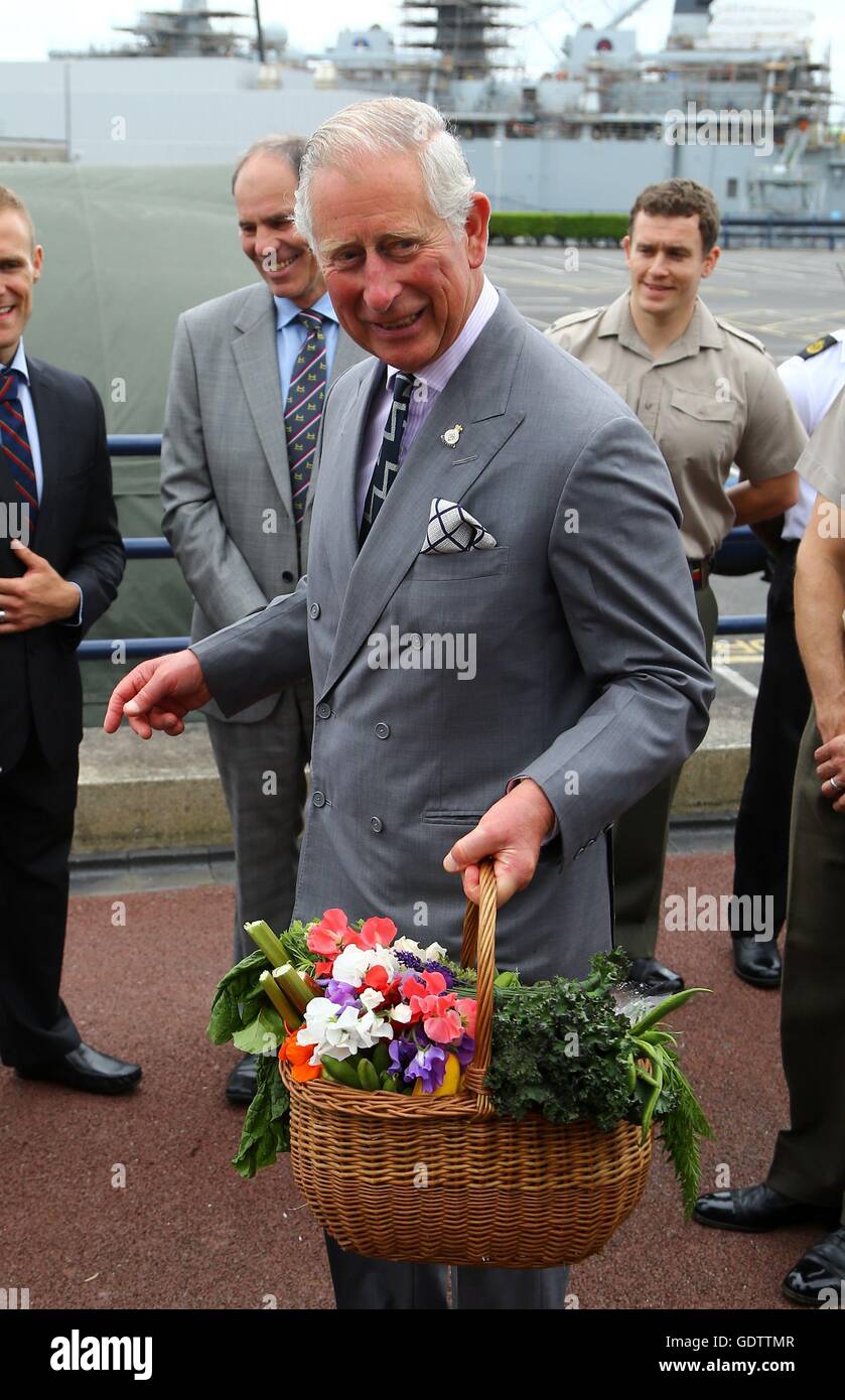 Le Prince de Galles, amiral de la flotte, porte un panier de fleurs et légumes cultivés fraîchement présentée à lui de Kezia Ormrod, fille de l'ancien combattant en Afghanistan Mark Ormrod, comme il a rencontré le personnel de la marine, lors d'une visite à Sa Majesté du chef de la base navale de Devonport, le troisième jour d'une visite annuelle à l'ouest du sud. Banque D'Images