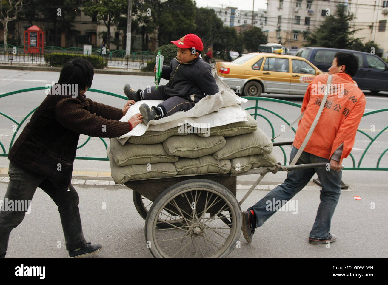 Un couple de migrants transportent le sable et leur enfant sur une charrette sur une route Banque D'Images