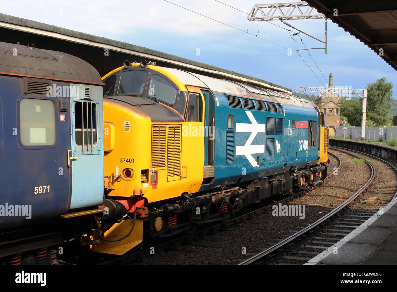 La classe 37 dans la locomotive diesel-électrique British rail grand logo livery entrée Comunidad de la gare avec un train de voyageurs. Banque D'Images