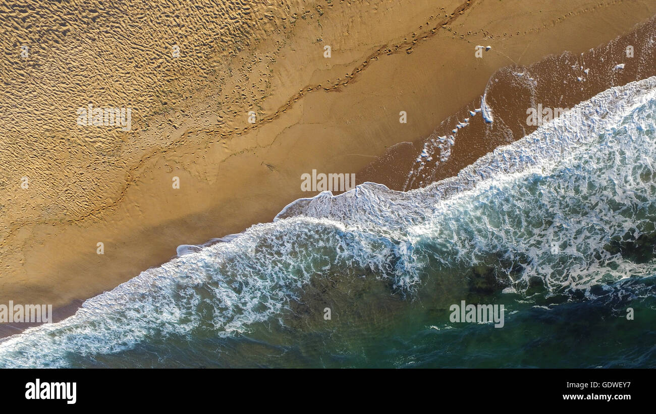 Image aérienne des vagues de la mer se brisant sur une plage solitaire dans un après-midi de fin d'été. Banque D'Images