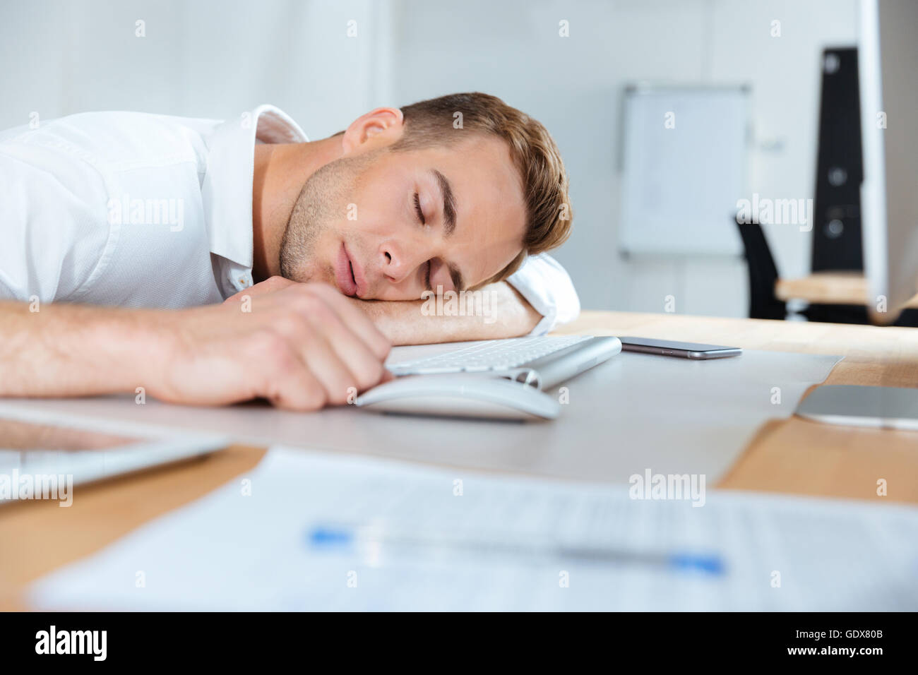Épuisé de fatigue young businessman dormir sur la table in office Banque D'Images