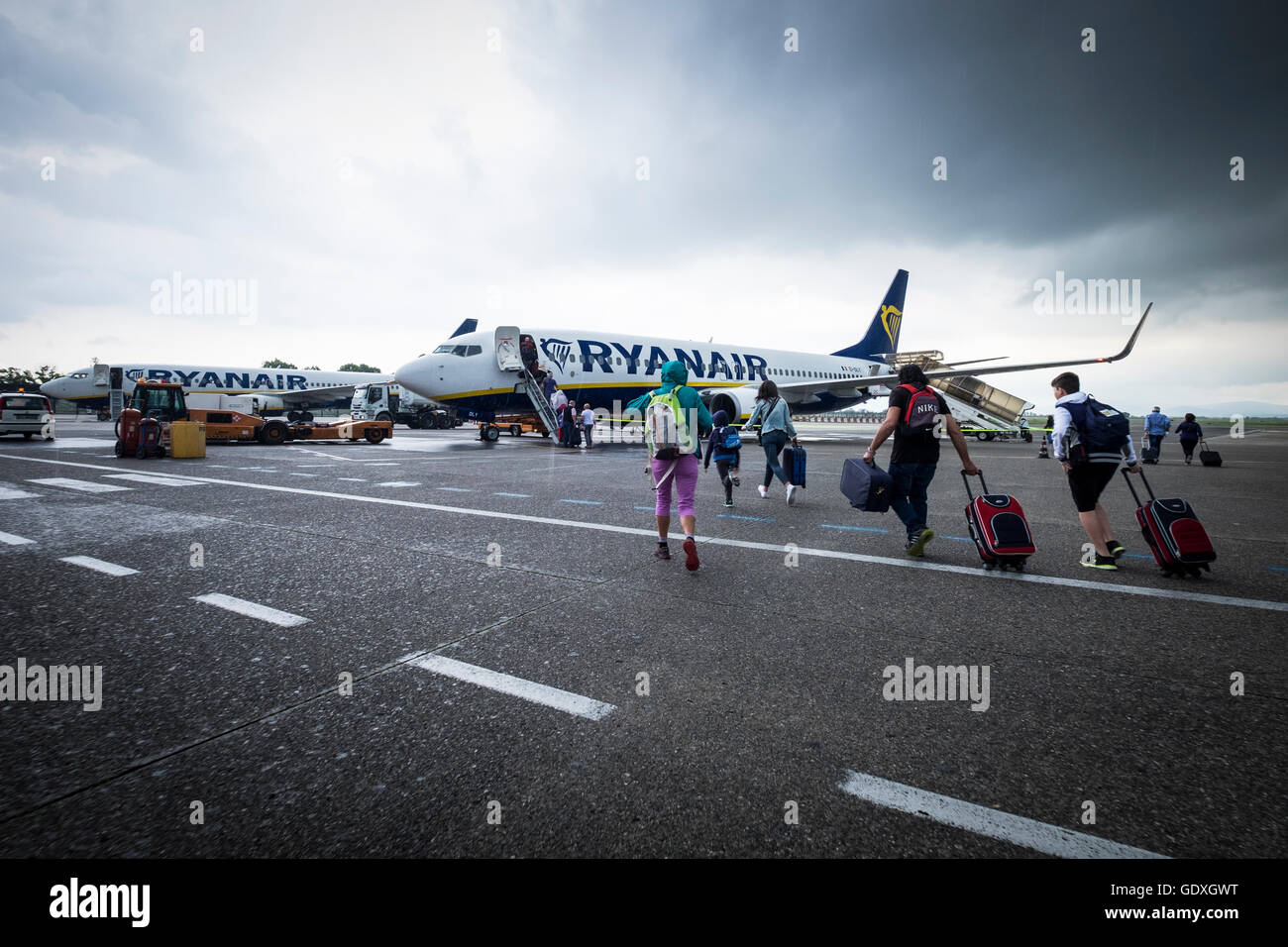Les passagers d'un vol Ryanair sous la pluie à l'aéroport Galileo Galilei de Pise, Toscane, Italie Banque D'Images