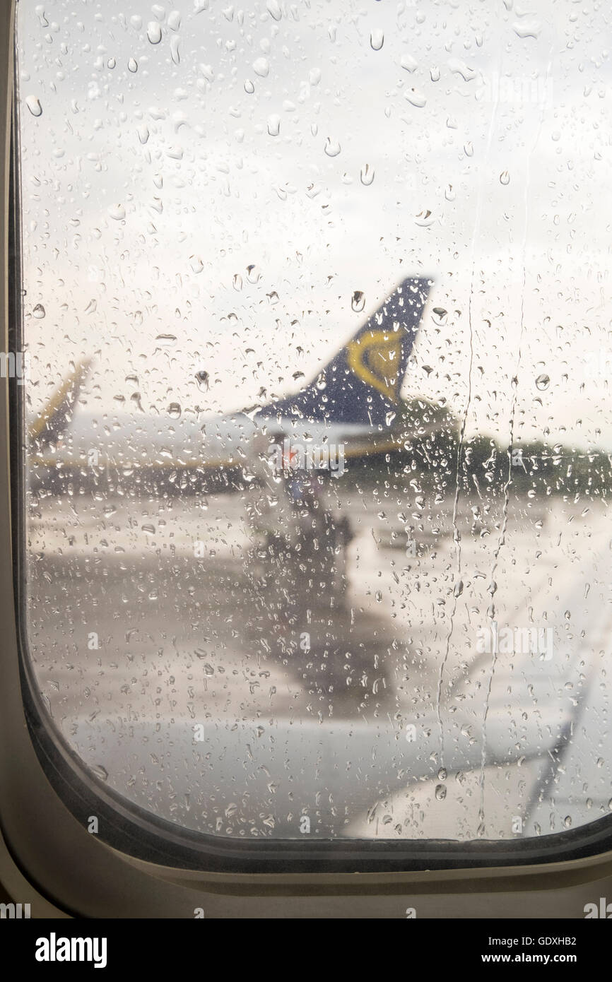 Gouttes de pluie sur la fenêtre d'un avion de Ryanair sur le tarmac en attente de départ, l'aéroport Galileo Galilei de Pise, Toscane, Italie Banque D'Images