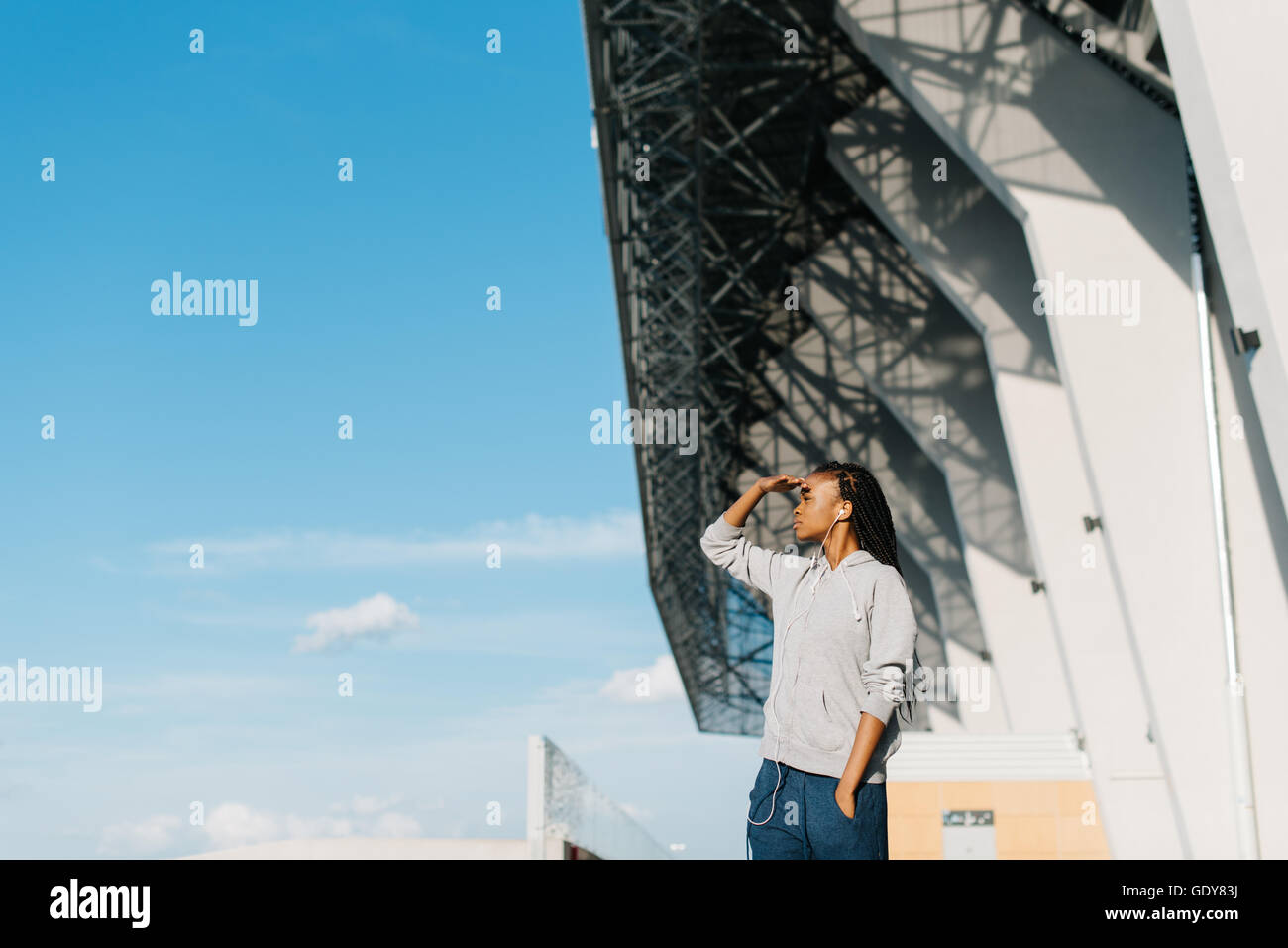 Vue latérale de courte vue african american woman avec de très longs cheveux, la main sur le front d'explorer ou de regarder loin Banque D'Images