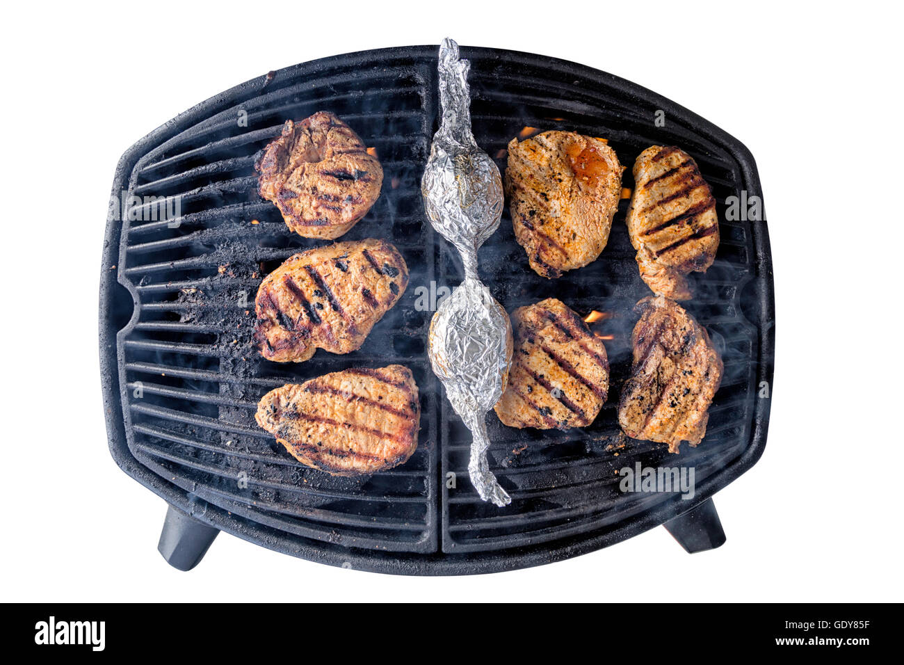 Porkchops sur un gril de barbecue isolé sur blanc avec chemin de détourage, les flammes et la fumée venant de c Banque D'Images