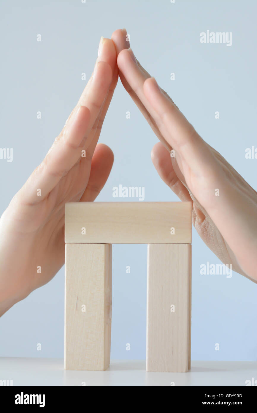 Chambre à partir de blocs de jouets isolé sur fond blanc avec des mains comme toit Banque D'Images