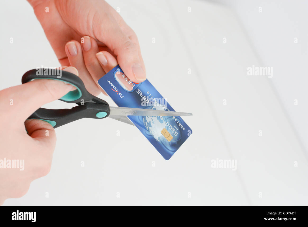 Femme coupe les mains une carte de crédit avec des ciseaux bleu isolé sur fond blanc Banque D'Images