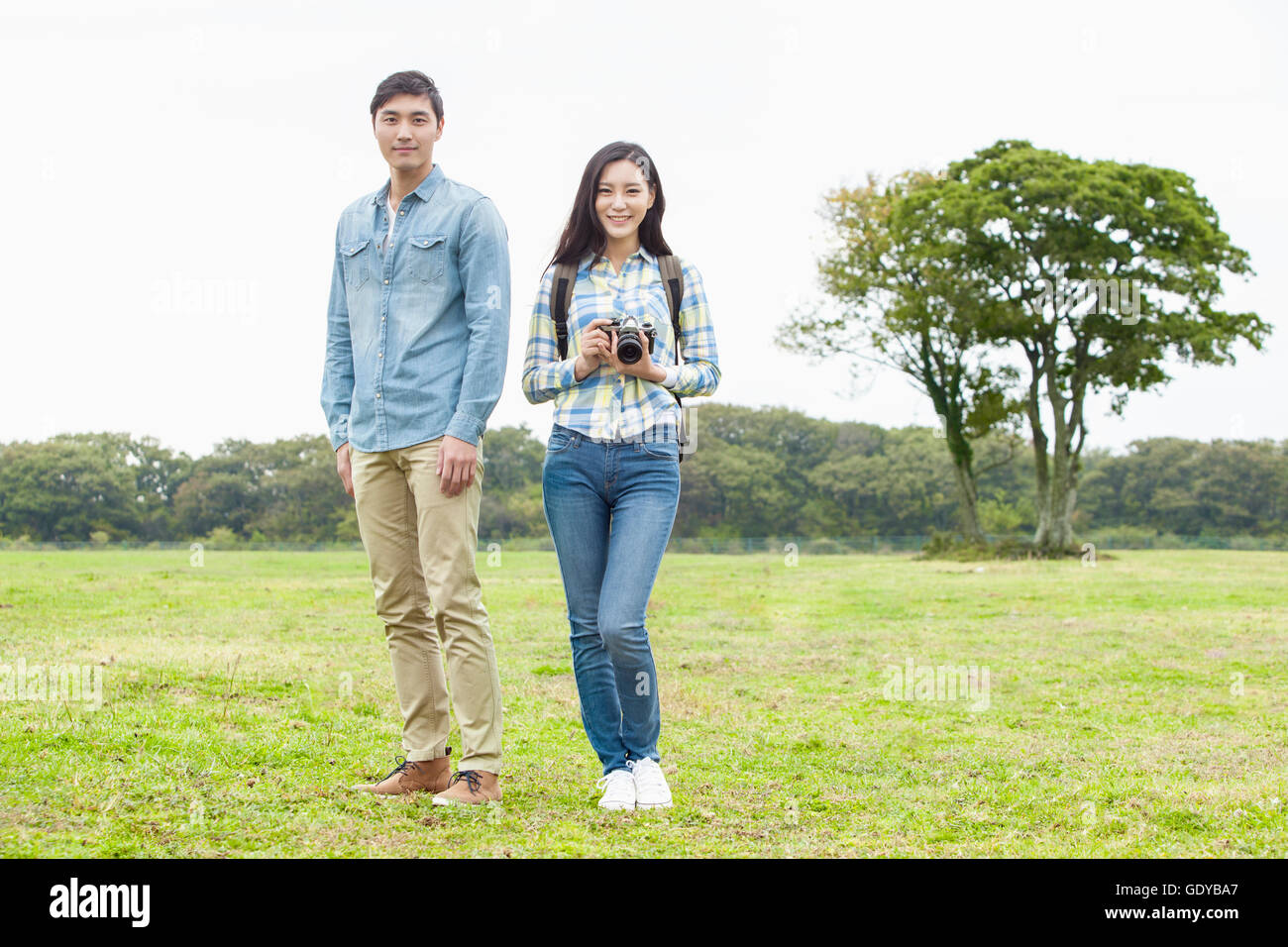 Young smiling couple standing avec un appareil photo sur les herbages Banque D'Images