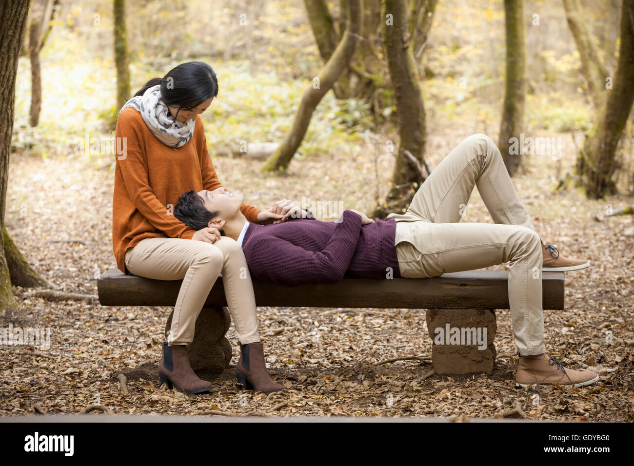 Jeune couple ayant une date sur un banc en forêt en automne Banque D'Images