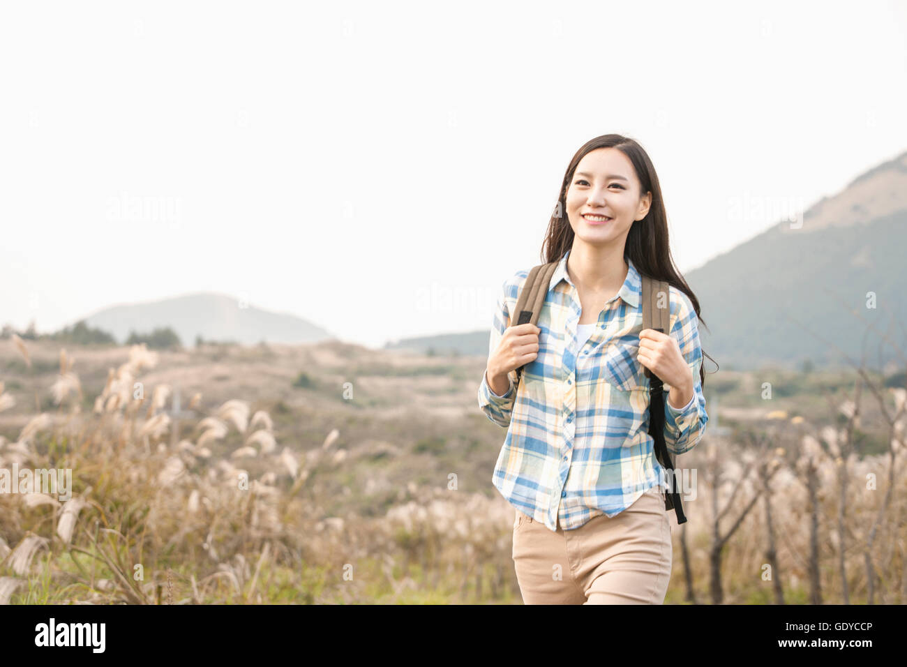 Young female backpacker contre un champ et les montagnes Banque D'Images