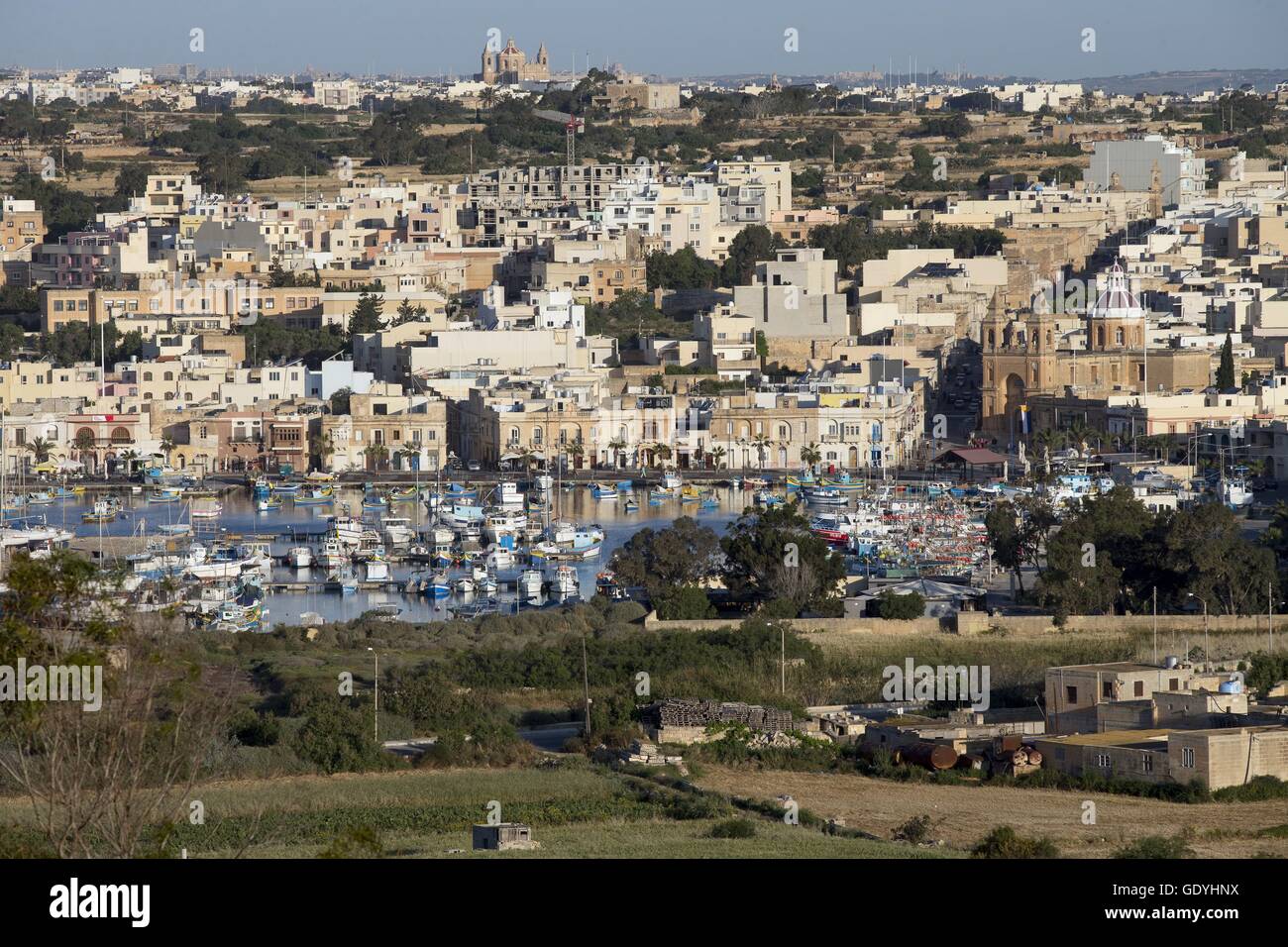 Bateaux de pêche peintes de couleurs vives (appelés Luzzu) dans le port du village de pêcheurs de Marsaxlokk, dans le sud de l'île de Malte. La photo a été prise en avril 2014. À droite est la paroisse "Notre-Dame de Pompéi". Photo : Tom Schulze | conditions dans le monde entier Banque D'Images