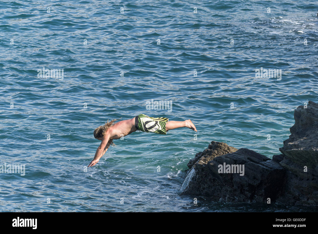 Le voyageur plonge dans la mer au large de roches sur la pointe à Newquay, Cornwall. Banque D'Images