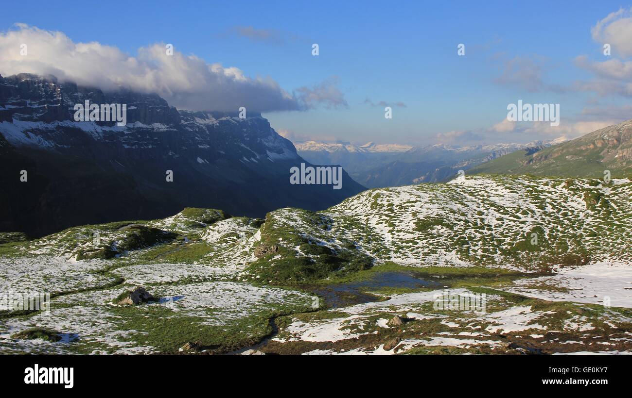 Verte prairie avec étang, la vallée et les montagnes. Nouvelle neige en été. Alpes suisses. Banque D'Images