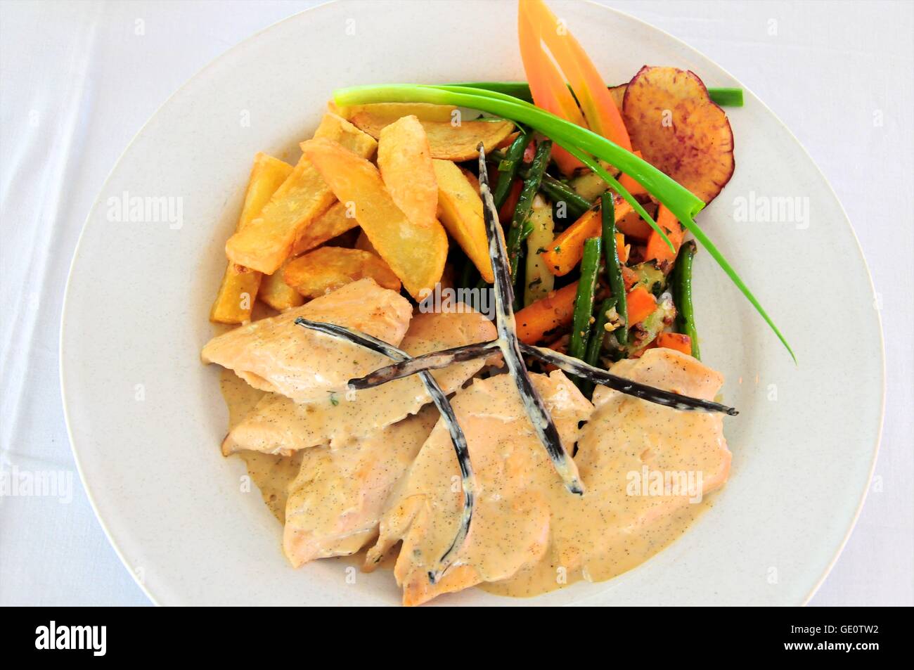 Escalopes de poulet avec sauce à la vanille, les quartiers de pommes de terre et légumes mixtes, garnie de gousses de vanille Banque D'Images