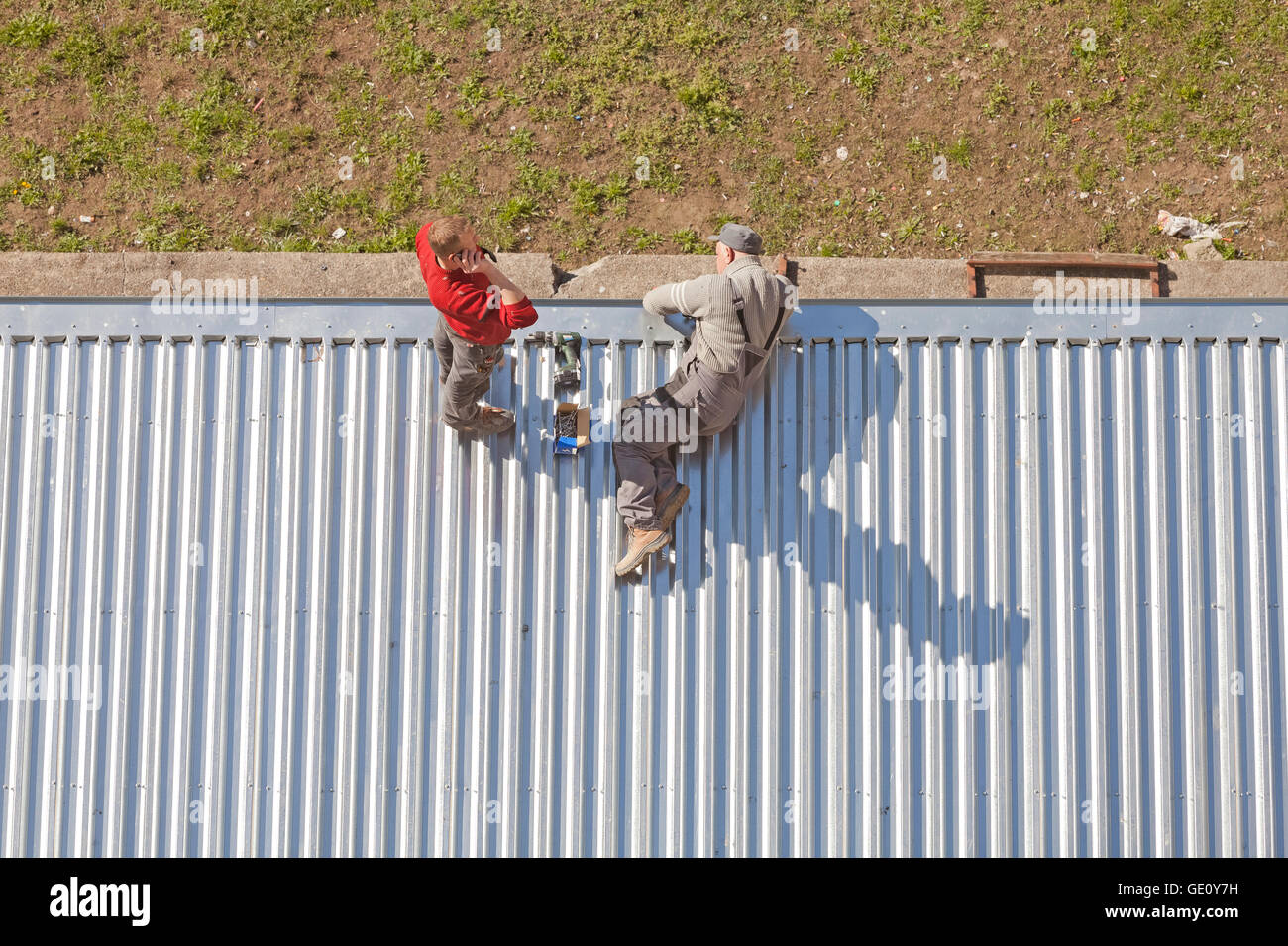 Szczecin, Pologne - 07 Avril 2016 : deux hommes travaillant sur un toit en tôle ondulée de magasin de feuilles de métal, photo prise d'en haut. Banque D'Images