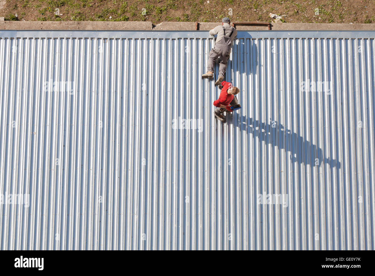 Szczecin, Pologne - 07 Avril 2016 : Les travailleurs de la réparation d'un store toiture en feuilles de métal ondulé, photo prise d'en haut. Banque D'Images