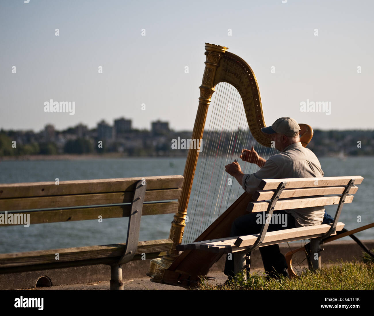 Harpiste musicien performeur s'asseoir sur un banc près de la mer à Vancouver, Canada Banque D'Images