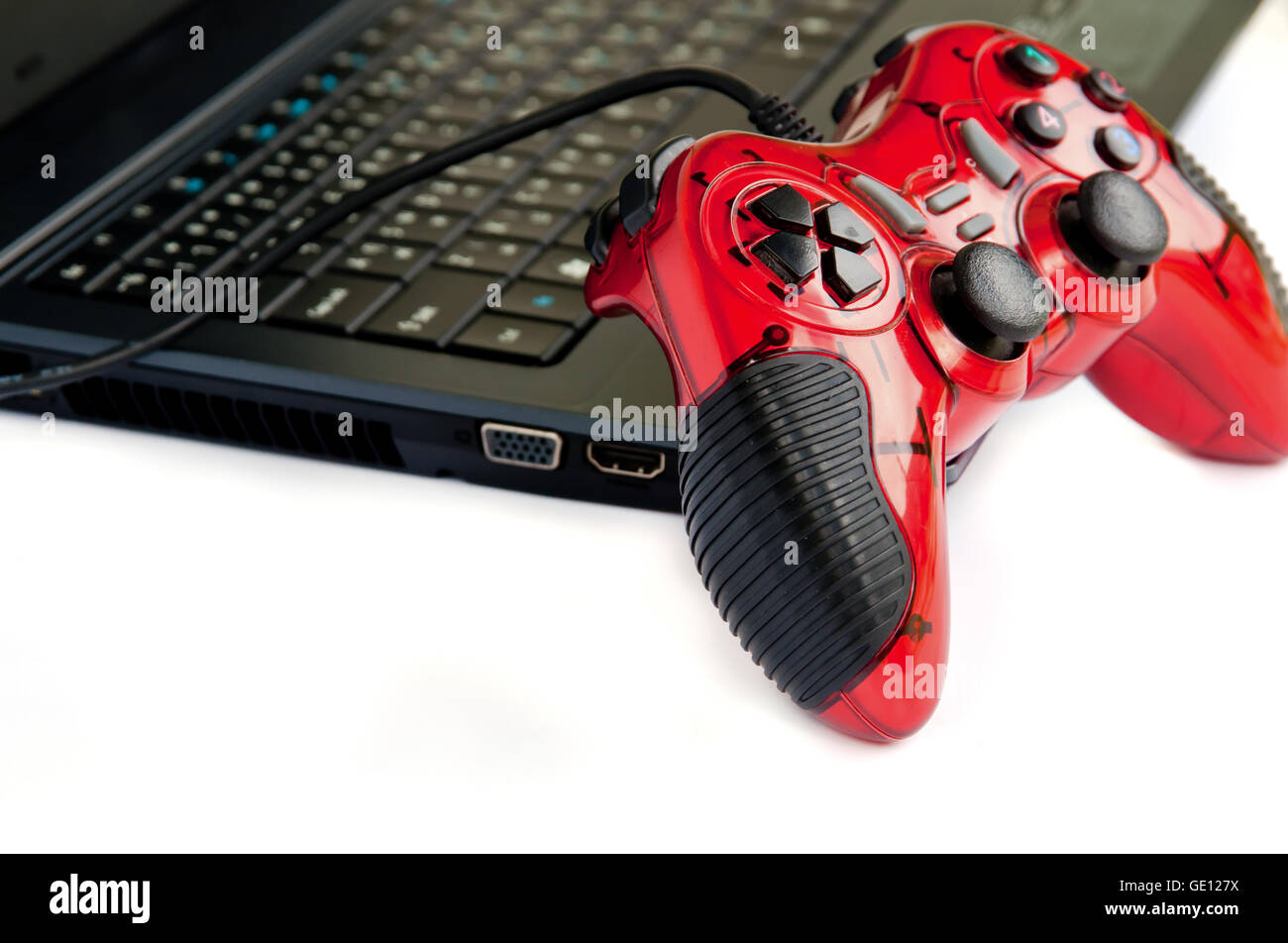 Contrôleur de jeu joystick rouge sur un ordinateur portable isolé sur fond blanc. Banque D'Images