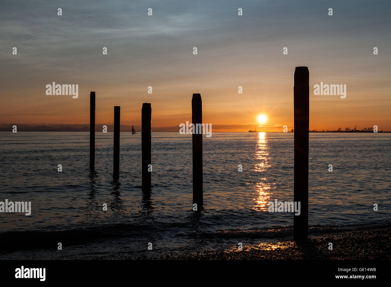 Bateau à voile sur l'océan Pacifique au coucher du soleil à Point Roberts, avec les postes sur le premier plan, l'état de Washington, USA Banque D'Images