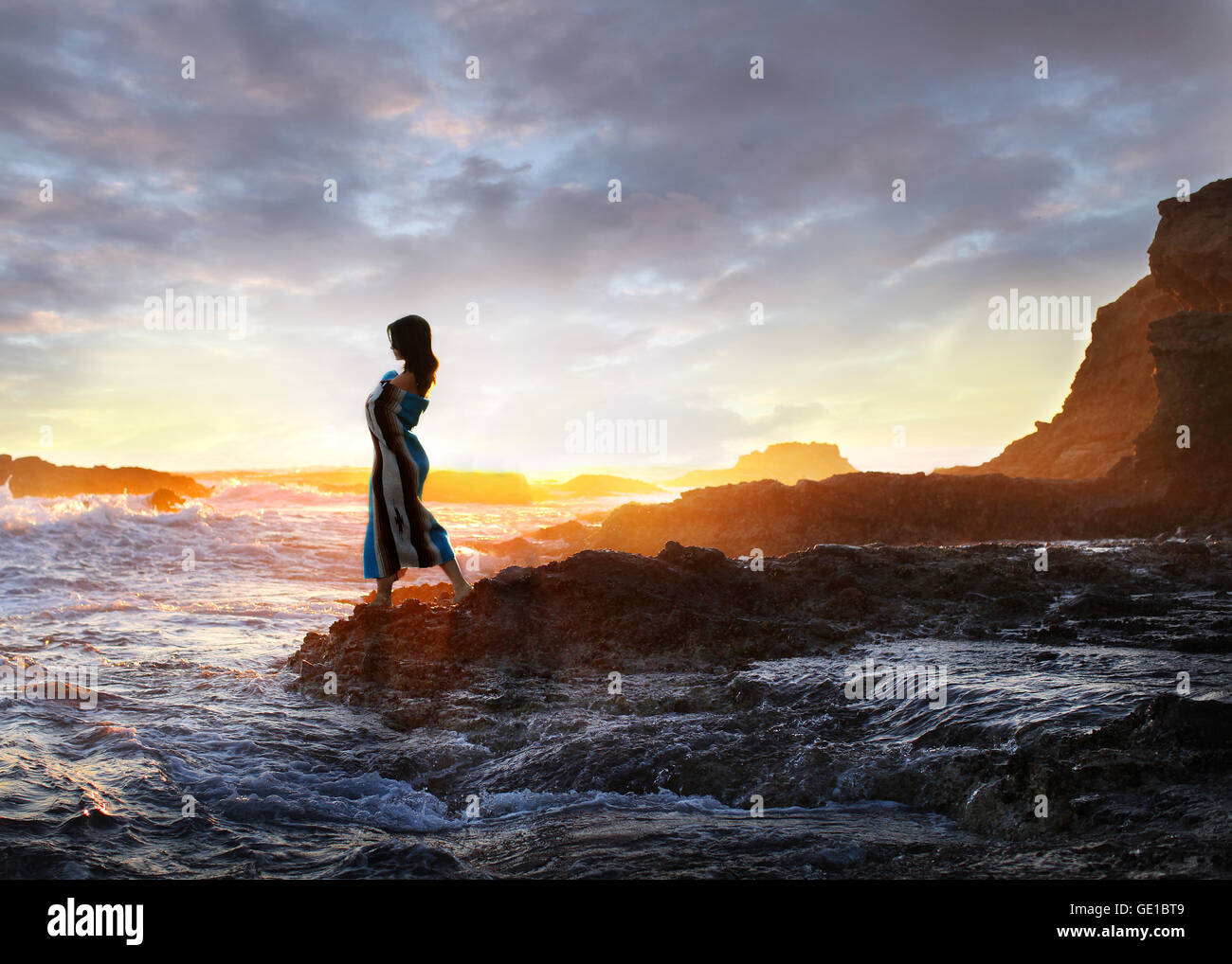 Femme debout sur des rochers au bord de l'océan au coucher du soleil, Orange County, Californie, États-Unis Banque D'Images