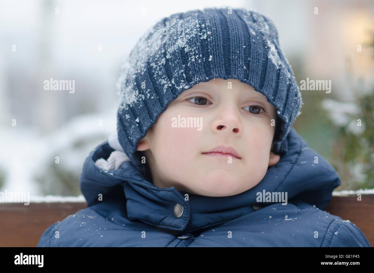 Portrait d'un garçon assis sur un banc dans la neige Banque D'Images
