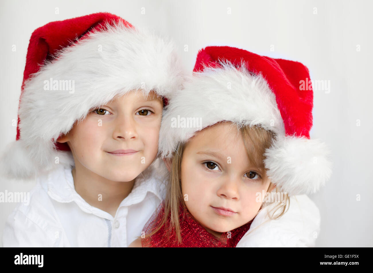 Portrait of boy and girl wearing christmas santa hats Banque D'Images