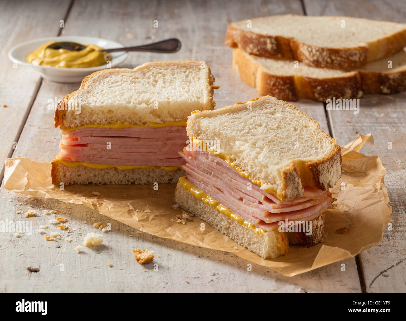 Un sandwich à la viande fumée sur une table en bois avec la moutarde. Banque D'Images