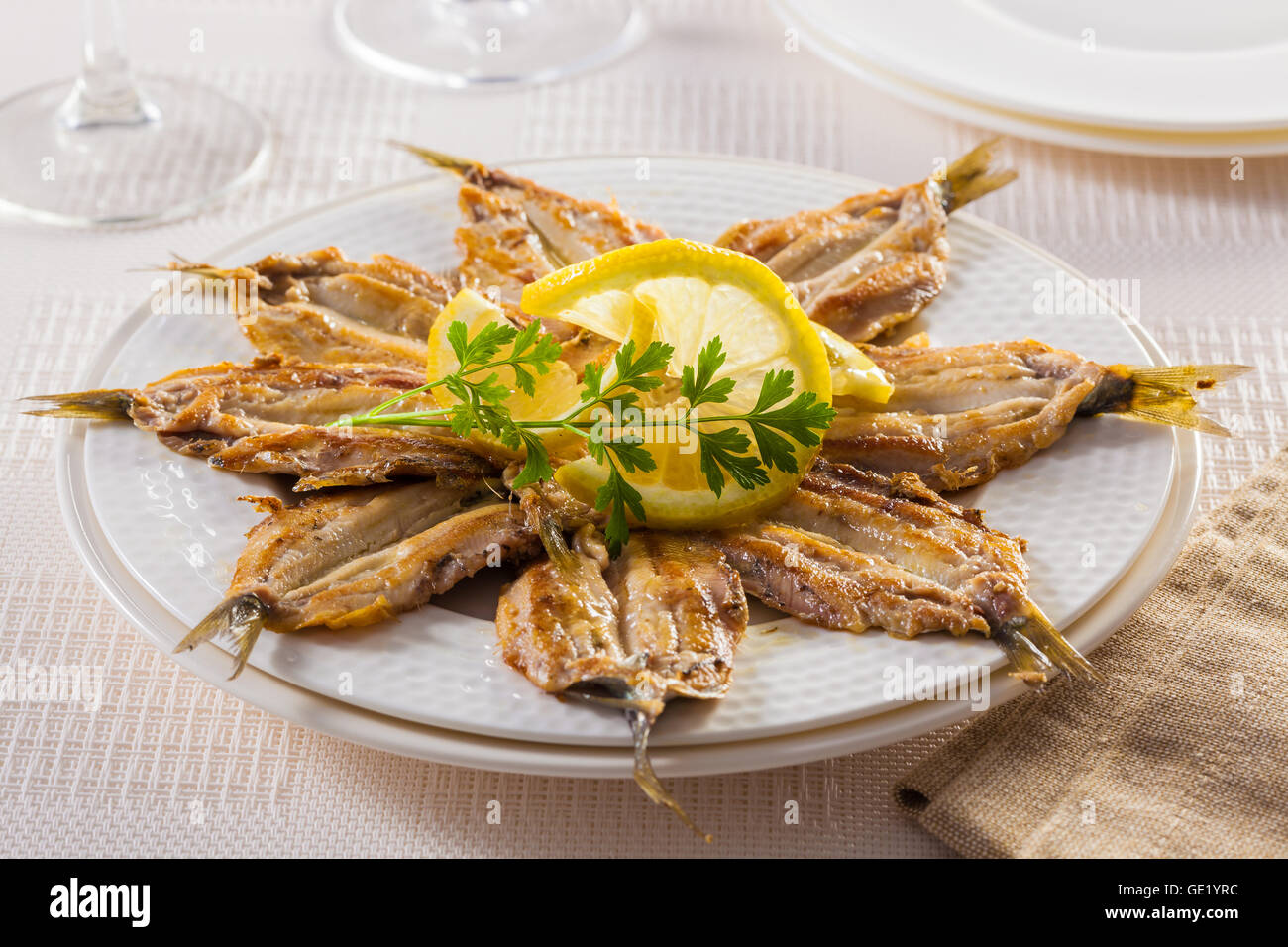 Filets de sardine frit servi sur une assiette avec du citron et le persil. Banque D'Images
