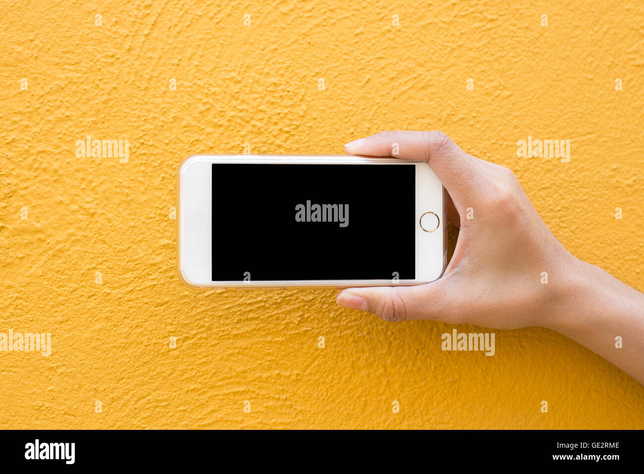 Hand holding Smartphone blanc sur fond de mur jaune Banque D'Images