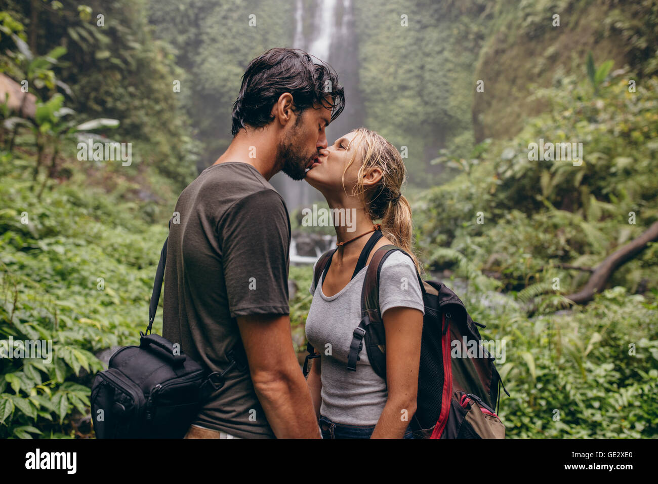 Shot de loving couple tout en se tenant dans la forêt. Couple in love kissing près d'une chute en forêt. Banque D'Images
