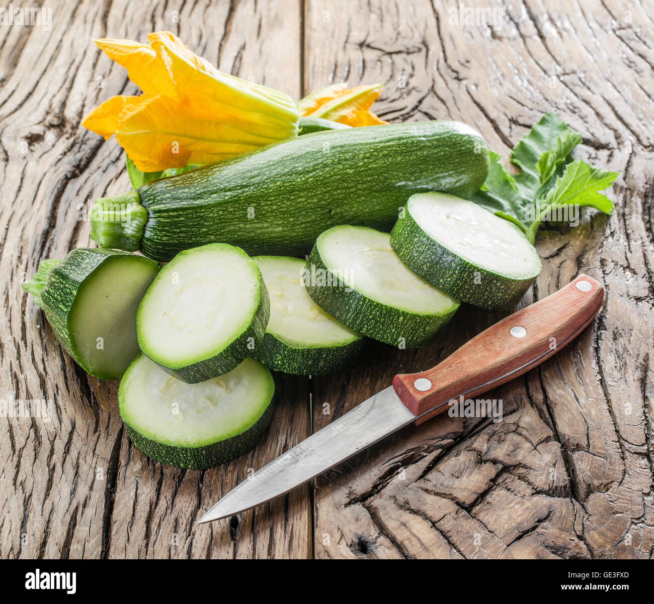 Avec des tranches de courgettes et fleurs de courgettes sur une table en bois. Banque D'Images