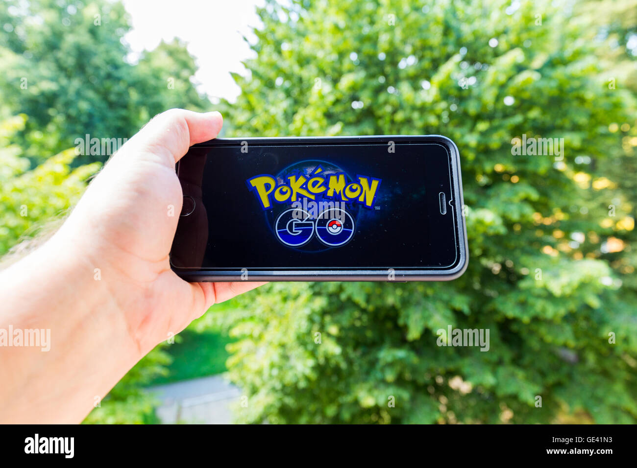 Apple iPhone6 Plus tenu dans une main montrant son écran avec Pokemon Rendez-application. Banque D'Images