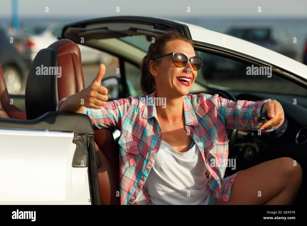 Jolie Jeune femme assise dans une voiture décapotable avec les clés en main - concept de l'achat d'une auto ou d'une voiture de location Banque D'Images
