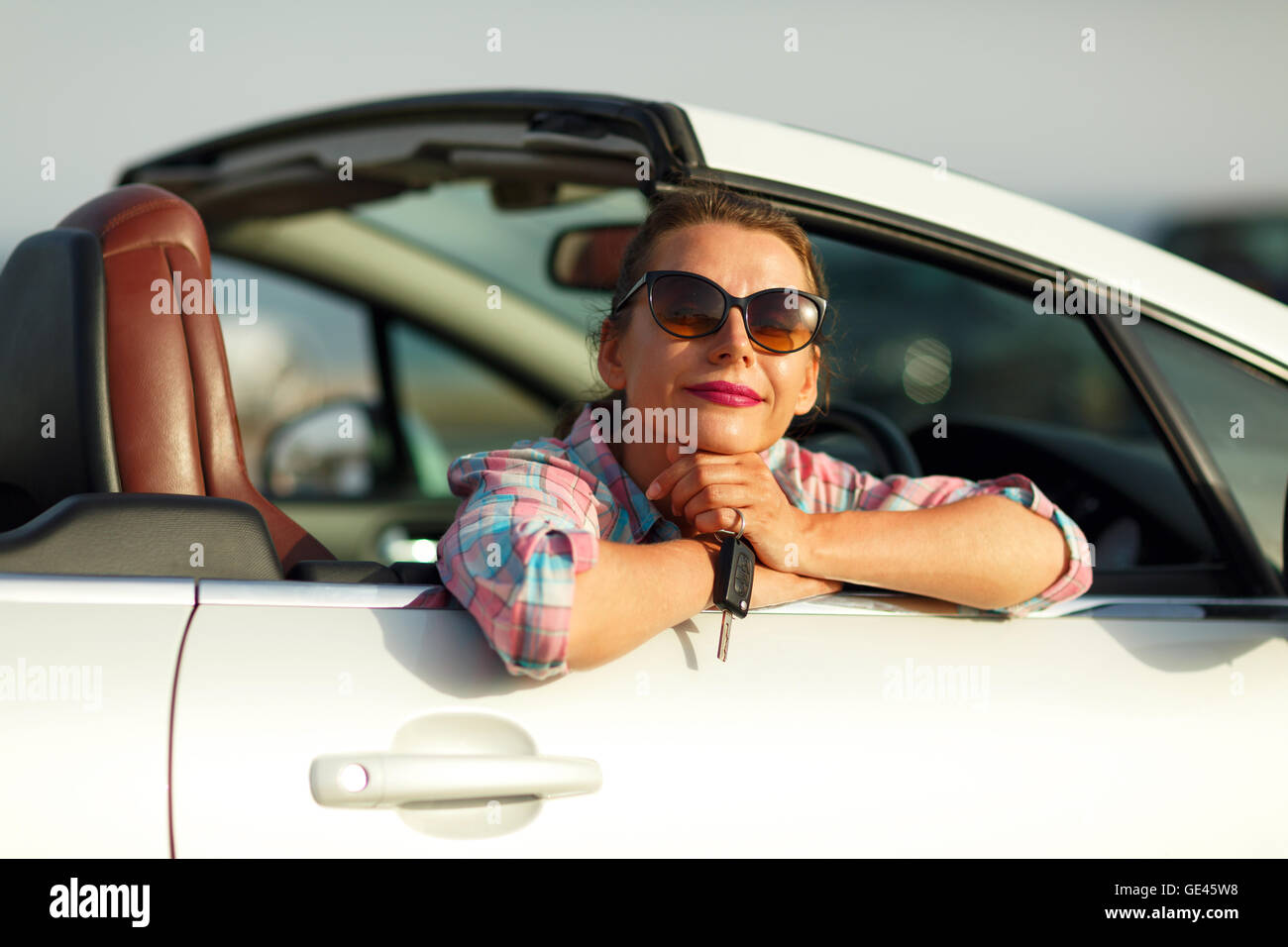 Jolie Jeune femme assise dans une voiture décapotable avec les clés en main - concept de l'achat d'une auto ou d'une voiture de location Banque D'Images