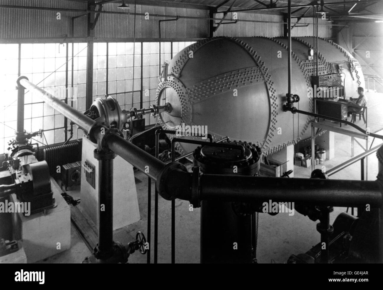 Cette vue extérieure de la turbine à cylindrée variable (VDT) montre le moteur d'entraînement, la tuyauterie du compresseur d'air et un opérateur sur le panneau de commande. L'équipement est utilisé pour des applications industrielles de puissance. Banque D'Images