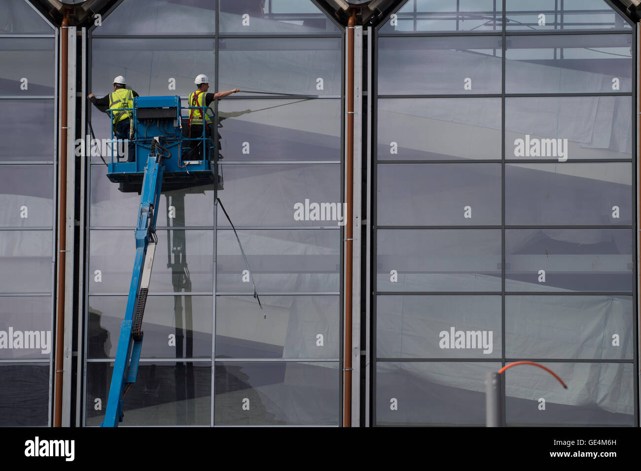 Les travaux de construction au Royaume-Uni : deux travailleurs dans une plate-forme 'cherry picker" travaillant à l'extérieur du vitrage d'un nouveau Tesco un magasin Marks & Spencer, Aberystwyth Wales UK Banque D'Images