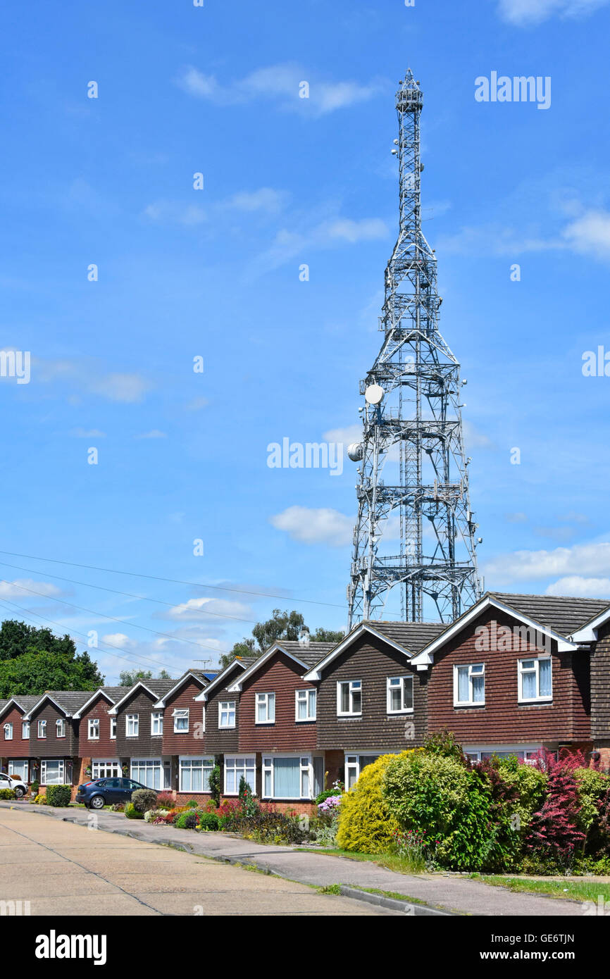 Antenne radio BT et antennes paraboliques dominant la façade répétitive d'un logement dans la rue résidentielle de banlieue Kelvedon Hatch Brentwood Essex, Angleterre Banque D'Images