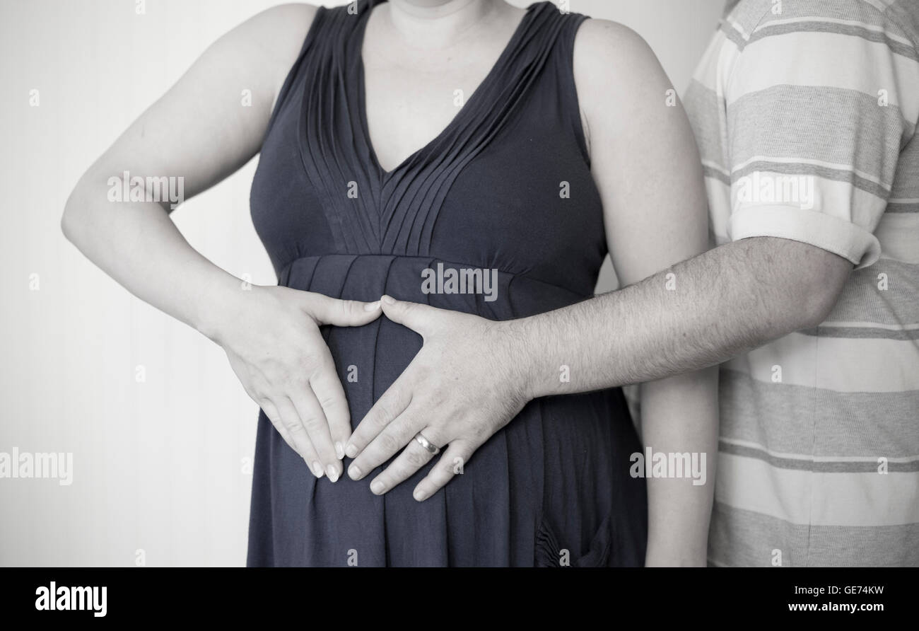 Femme enceinte et mari affectueux embrassant le ventre à la maison Banque D'Images
