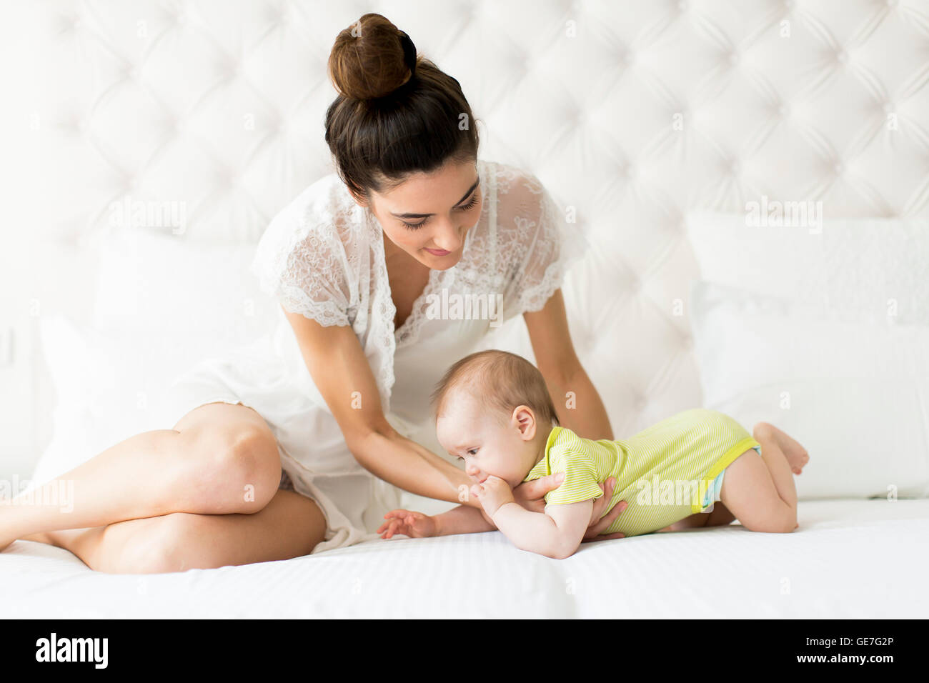 Jeune maman avec un bébé sur le lit Banque D'Images