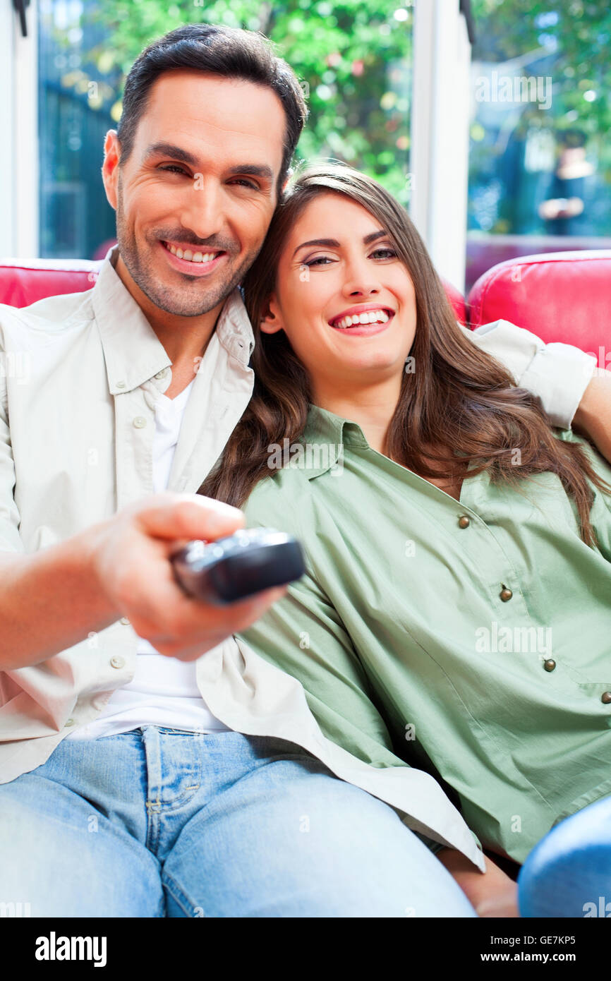 Portrait of happy young couple watching TV. Les partenaires masculins et féminins sont sur un canapé. Ils sont assis à la maison. Banque D'Images