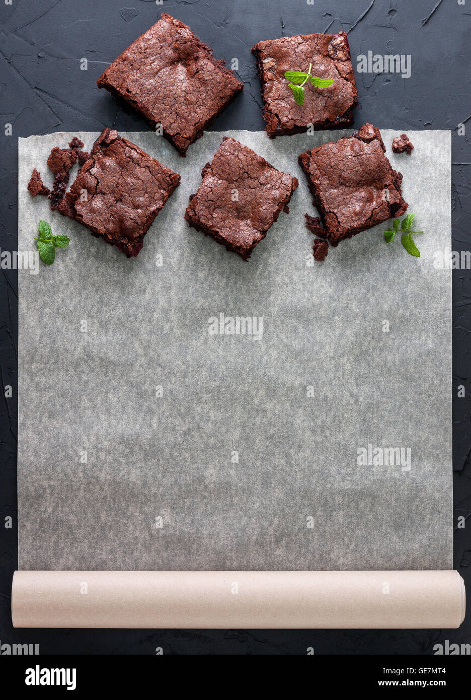 Quelques morceaux de chocolat sur du papier sulfurisé avec espace d'information (vue de dessus). arrière-plan foncé béton noir. Banque D'Images