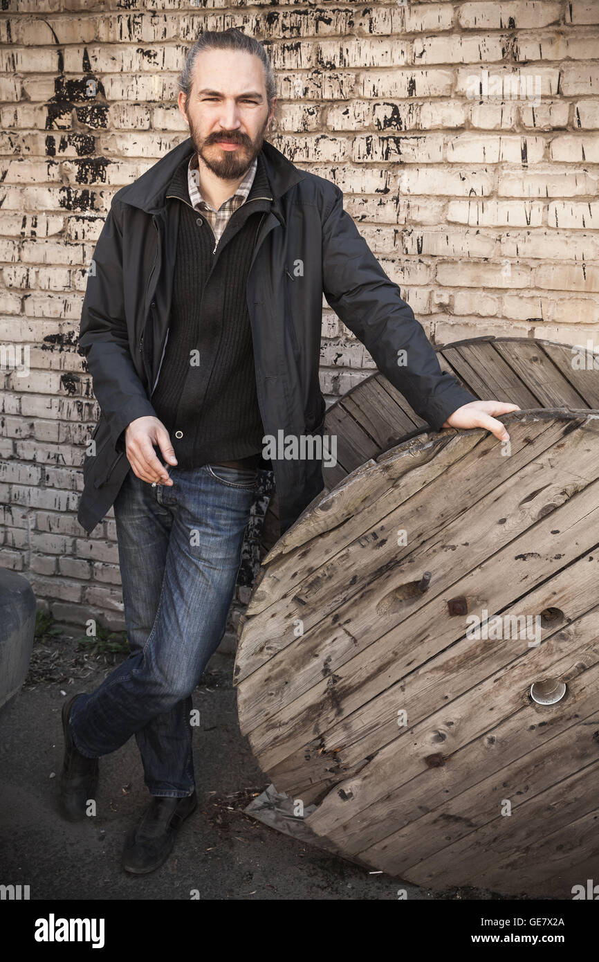 Vertical extérieur portrait of young Asian Man in Black au mur de brique gris grungy urban background Banque D'Images