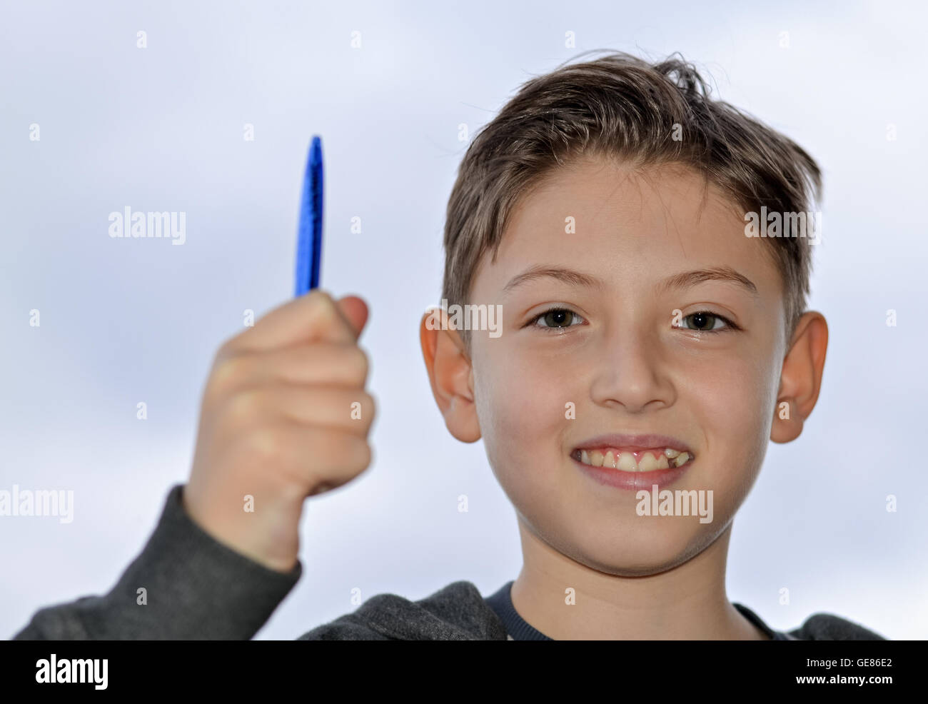 Heureux et intelligent jeune garçon tenant un stylo dans sa main Banque D'Images