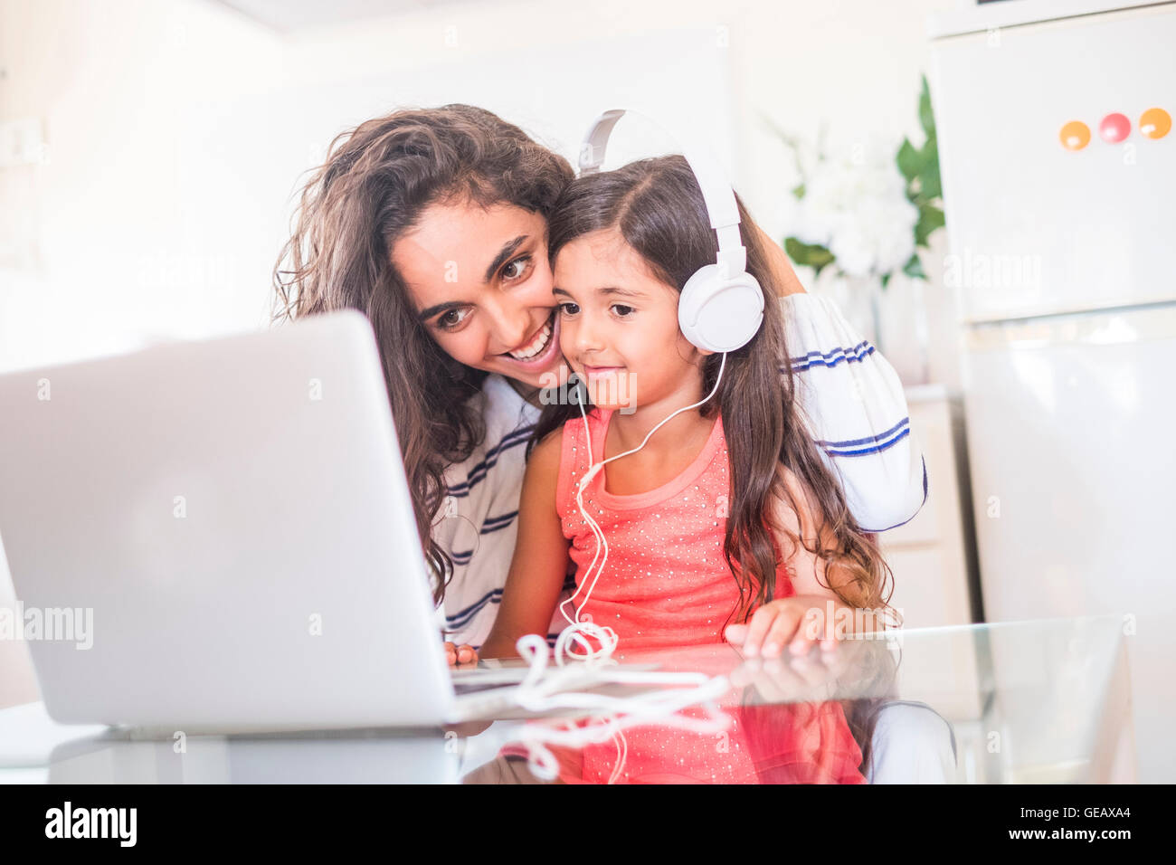 Teenage girl et sa petite sœur avec ordinateur portable et un casque Banque D'Images